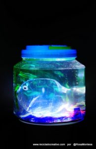 Pez hecho con una botella de plástico, dentro de una pecera con botellas de PET